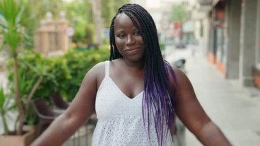 Afro-Amerikalı kadın gülümsüyor. Kahve dükkanının terasında güçlü hareketler yapıyor.