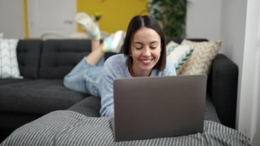 Evdeki kanepede dizüstü bilgisayar kullanan güzel İspanyol kadın.