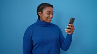 Elinde dolarlarla gülümseyen Afrikalı Amerikalı kadın ve izole edilmiş mavi arka plan üzerinde akıllı telefon.