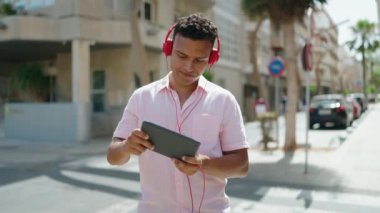 Sokakta video oyunu oynarken kendinden emin gülümseyen genç Latin adam.