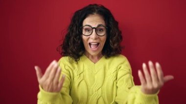 Orta yaşlı İspanyol kadın gülümsüyor. Kendine güveni tam. El kol hareketi yapıyor.