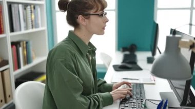 Kafkasyalı genç bir kadın kütüphane üniversitesinde bilgisayar kullanıyor.