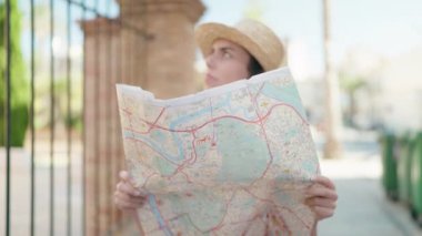 Genç İspanyol kadın turist gülümsüyor kendine güvenen şehir haritası caddede.