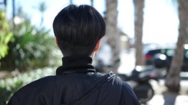 Genç Çinli kadın parkın arkasında dikiliyor.