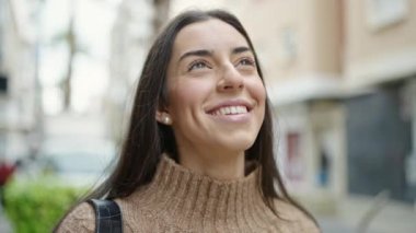 Young beautiful hispanic woman smiling confident looking to the sky at street