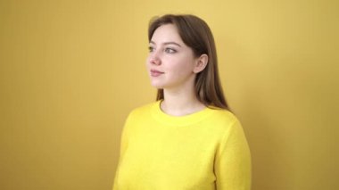 Young blonde woman smiling confident standing over isolated yellow background