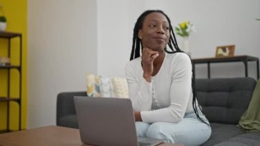 African american woman using laptop sitting on sofa at home