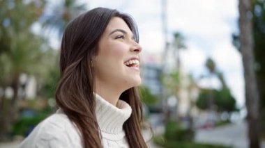 Genç ve güzel İspanyol kadın gülümsüyor. Kazanan yüz ifadesiyle caddede duruyor.