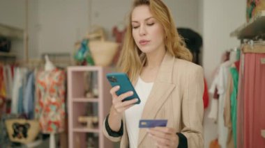 Akıllı telefon ve kredi kartı kullanan genç sarışın bir müşteri.