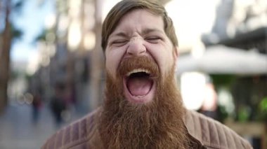 Young redhead man doing funny gesture with mouth at street