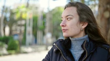 Young caucasian woman standing with serious expression at park