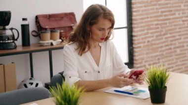 Genç, güzel İspanyol iş kadını. Ofisteki belgelerde akıllı telefon yazısını kullanıyor.