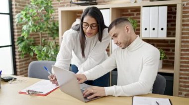 Man and woman business workers using laptop writing on document at office