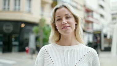 Genç sarışın kadın gülümsüyor. Kendine güvenen yeni arabanın anahtarını işaret ediyor.