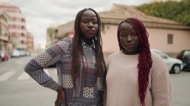 İki Afro-Amerikan kadını sokakta kendine güvenerek gülümsüyor.