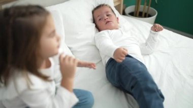 Adorable girl and boy laying on bed screaming and kicking at bedroom