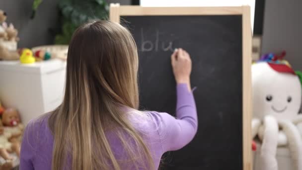 幼儿园时 年轻的金发女幼儿园老师在黑板上写着 — 图库视频影像