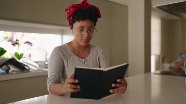 Afrykańska Amerykanka Czyta Książkę Siedząc Stole Domu — Wideo stockowe