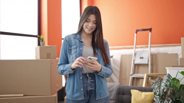 若い美しいですヒスパニック系の女性笑顔自信を持って使用してスマートフォンで新しい家 — ストック動画