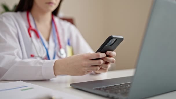 年轻美丽的惊慌失措的女医生在诊所使用笔记本电脑和智能手机 — 图库视频影像