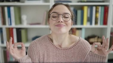 Kütüphanede yoga egzersizi yaparken bilgisayar kullanan güzel İspanyol bir kız öğrenci.