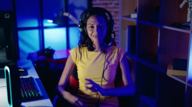 Genç, Afro-Amerikalı, gülümseyen, kendine güveni tam, kumar salonunda kollarını kavuşturmuş bir şekilde oturuyor.