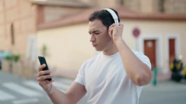 Genç İspanyol adam sokakta müzik dinliyor.