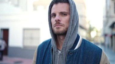 Young caucasian man standing wearing hoodie with serious expression at street