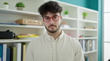 Young hispanic man student smiling confident standing at library university