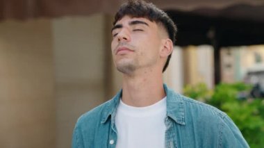 Sokakta gözleri kapalı nefes alan genç bir İspanyol.