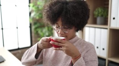 Genç afro-amerikan kadın iş kadını gülümsüyor ofisteki kahveleri kokluyor