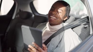Sokakta arabada oturan Afrikalı Amerikalı kadın dokunmatik ped kullanıyor.