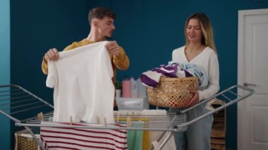 Young couple smiling confident hanging clothes on clothesline at laundry room