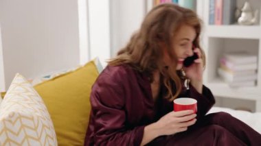 Genç, güzel, İspanyol bir kadın. Akıllı telefondan konuşuyor. Yatak odasında kahve içiyor.