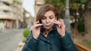 Orta yaşlı kadın sokakta kendine güvenen gözlüklü gülümsüyor.