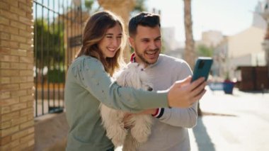 Young couple holding dog having video call at street