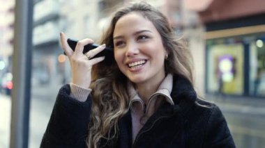 Genç ve güzel İspanyol kadın gülümsüyor. Caddedeki akıllı telefondan kendine güvenen bir sesli mesaj dinliyor.