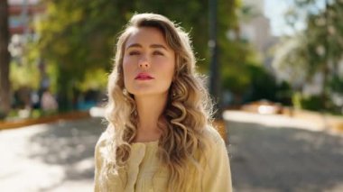 Rahat yüzü olan genç sarışın kadın parka doğru gökyüzüne bakıyor.