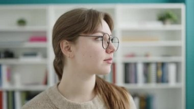 Young blonde woman student smiling confident standing at library university