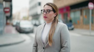 Sokakta ciddi bir ifadeyle duran genç bir kadın yönetici.