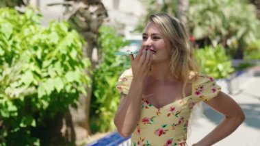 Genç, güzel İspanyol kadın gülümsüyor. Parktaki akıllı telefondan konuşuyor.