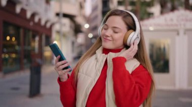 Young blonde woman smiling confident listening to music and dancing at street