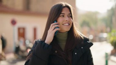 Genç İspanyol kadın gülümsüyor. Kendine güveniyor. Akıllı telefondan konuşuyor.