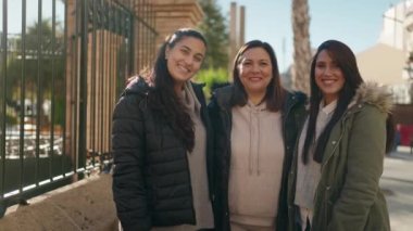 Anne ve kızları gülümsüyor. Kendilerine güveniyorlar. Akıllı telefondan özçekim yapıyorlar.