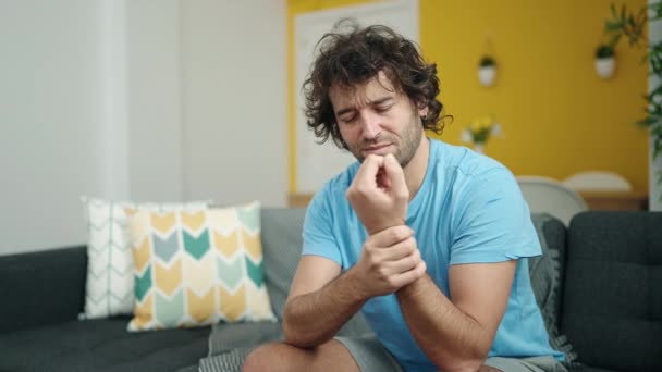 Young Hispanic Man Sitting Sofa Suffering Wrist Pain Home — Stok video