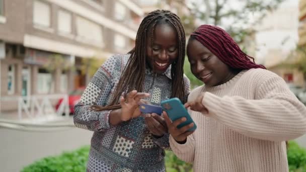 ストリートでスマートフォンとクレジットカードを使っているアフリカ系アメリカ人女性2人 — ストック動画