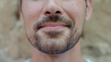 Genç İspanyol adam, izole taş arka planda kendinden emin bir şekilde gülümsüyor.