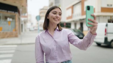 Genç İspanyol kadın gülümsüyor. Kendine güveni tam. Sokakta akıllı telefonun yanında selfie çekiyor.