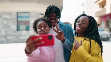 Afro-Amerikalı arkadaşlar yan yana durur, caddede akıllı telefonun yanında selfie çekerler.