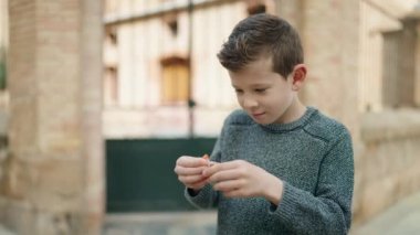 Sarışın çocuk, kendine güvenen, sokakta şeker yiyen.